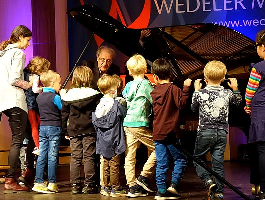 Grigory Gruzman erklärt den Kindern die Eigenschaften eines Klaviers