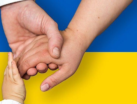 Hände halten einandern vor der ukrainischen Flagge