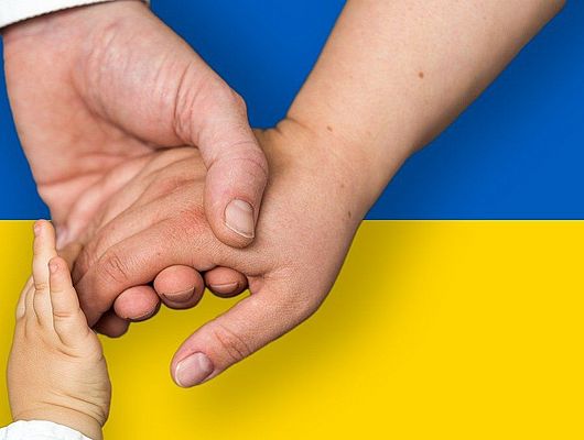 Hände halten einandern vor der ukrainischen Flagge