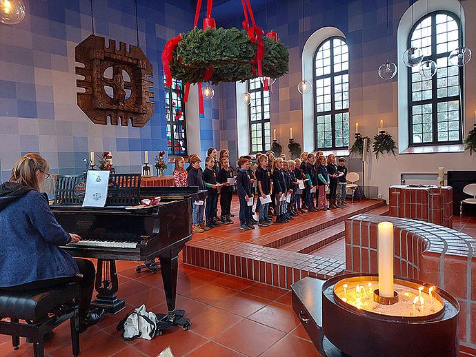Kinderchor in einer kirche, links im Bild die Lehrerin am Klavier. 
