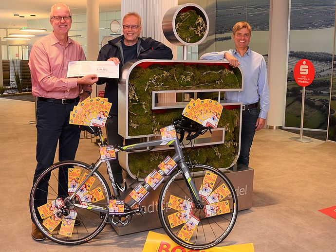 Das Rennrad ist nur Symbol: Mathias Bock gewann ein Bambus-Fahrrad und Jens Krippahle  (links) von der Stadtsparkasse sowie Franc Grimm vom Institut für vernetztes Denken  gratulierten