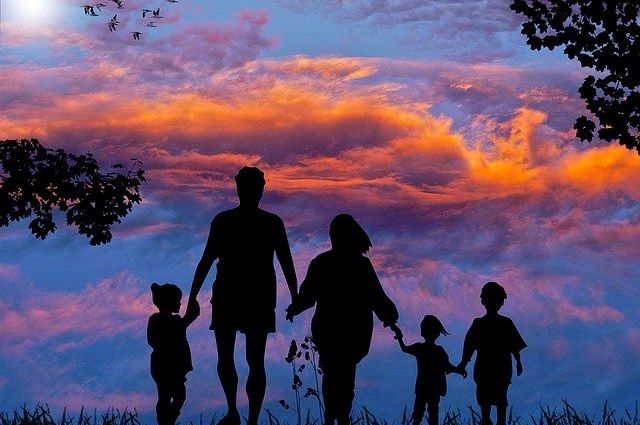 Eine Familien, Mutter Vater und drei Kinder, hält sich zusammen an den Händen