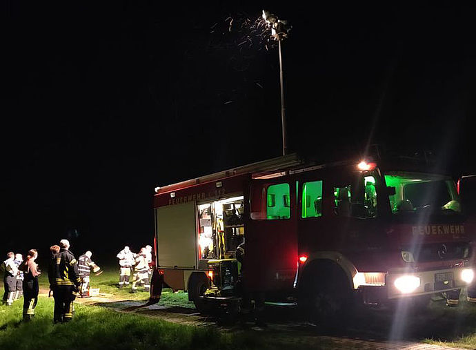 Ein Feuerwehrfahrzeug im Dunkeln am Deich mit mehreren Einsatzkräften