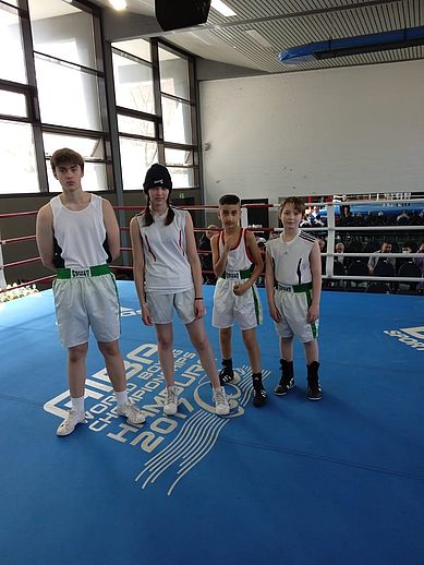 Vier junge Boxer auf der blauen Sportmatte lächeln in die kamera