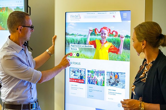 An einer der Digital-Stelen im Wedeler Rathaus ging Dirk Schrödter mit der 2. Stv. Bürgermeisterin der Stadt Wedel, Julia Fisauli, auf Entdeckungstour im Wedeler Stadtportal wedel.de . Foto: Stadt Wedel/Kamin