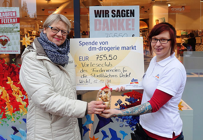 Nelly Englert (rechts) überreicht Annette Baars vom Förderverein der Stadtbücherei einen symbolischen Scheck über 755,50 Euro.