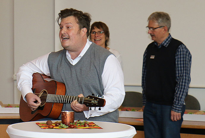 Mann mit Gitarre und zwei Personen im Hintergrund