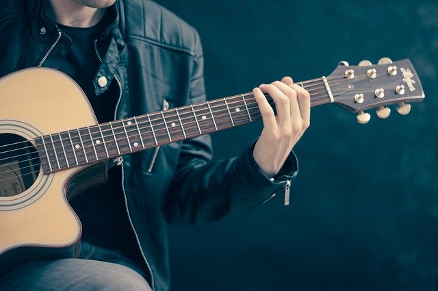 Ein Gitarrenspieler hält seine Akkustikguitarre