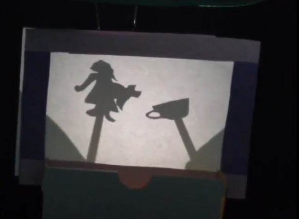 Bildausschnitt aus dem Schattentheater mit einer Mädchen-Figur und einer Teetasse
